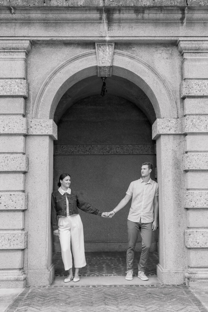 Black and White of a couple holding hands under an arch at Crane Estate