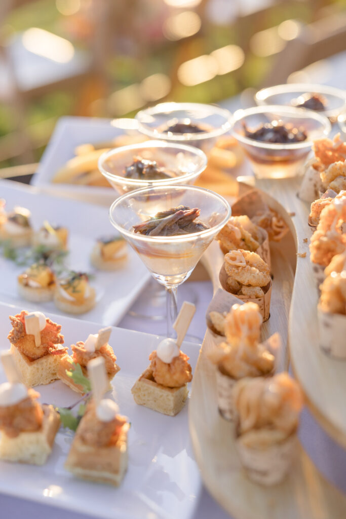Cocktail hour bites and champagne coupes styled on a reception table during golden hour, capturing the elevated guest experience often documented by Massachusetts wedding photographers.