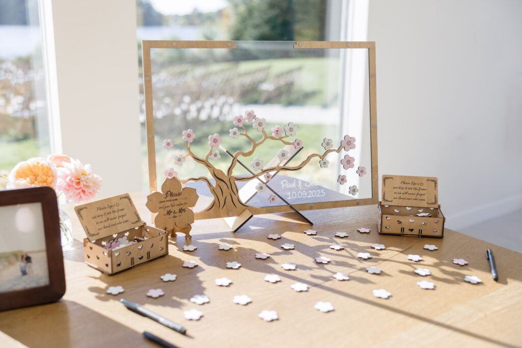Wooden guest book display with a floral tree design and personalized name pieces arranged for guests to sign at the reception, photographed as part of a thoughtful Massachusetts wedding day gallery.