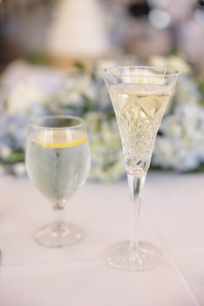 Crystal champagne flute and lemon water glass styled on a softly lit reception table during cocktail hour, adding an editorial detail moment to this Massachusetts wedding photography gallery.