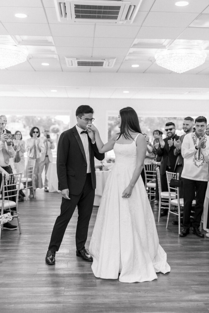 Newly married couple shares their first dance surrounded by cheering guests in a black-and-white reception image, capturing the lively atmosphere found at some of the best wedding venues in Massachusetts.
