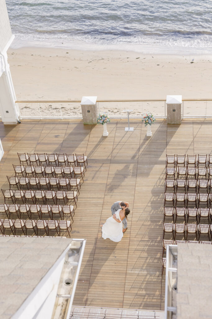 Aerial-style view of a waterfront ceremony setup with rows of chairs facing the beach and ocean beyond, showcasing one of the more scenic waterfront wedding venues Massachusetts couples often love.